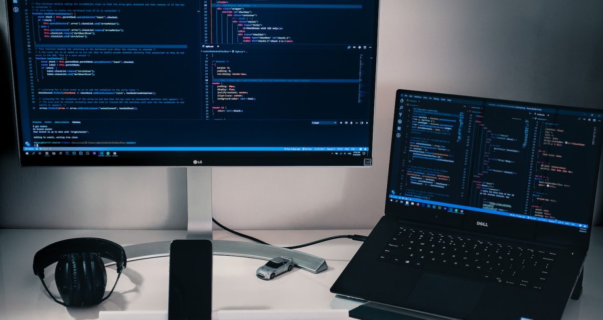laptop computer beside monitor with keyboard and mouse